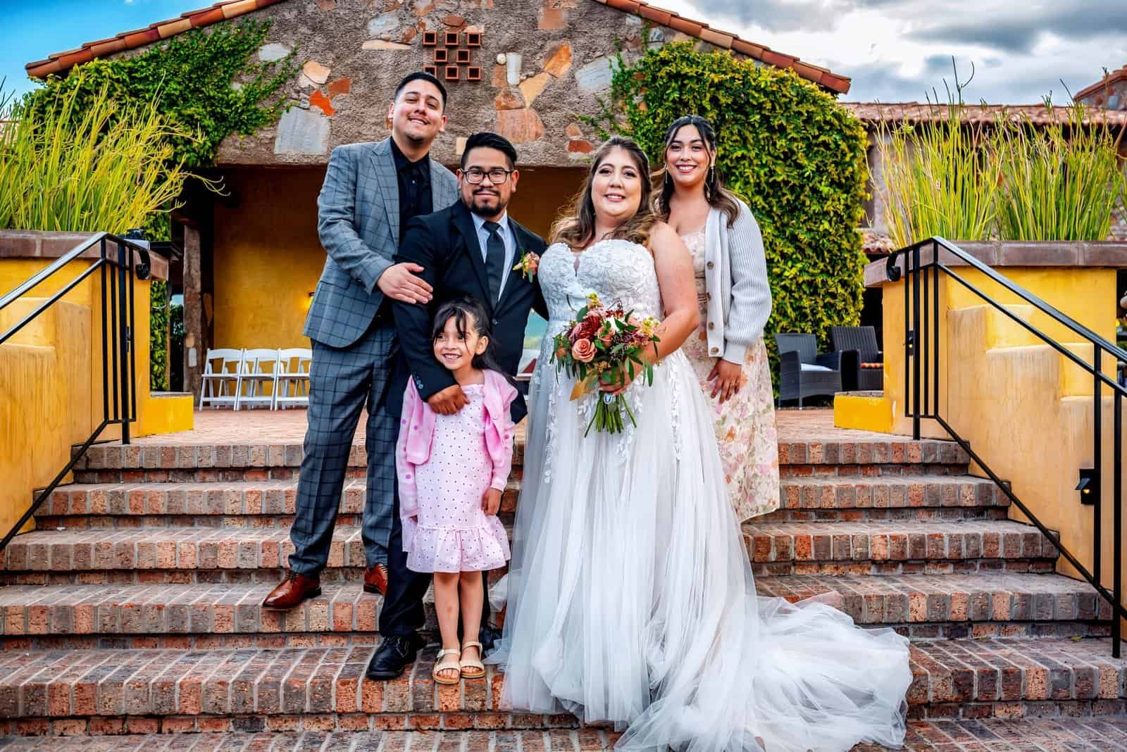 Joyful wedding moment with family and friends on outdoor steps.