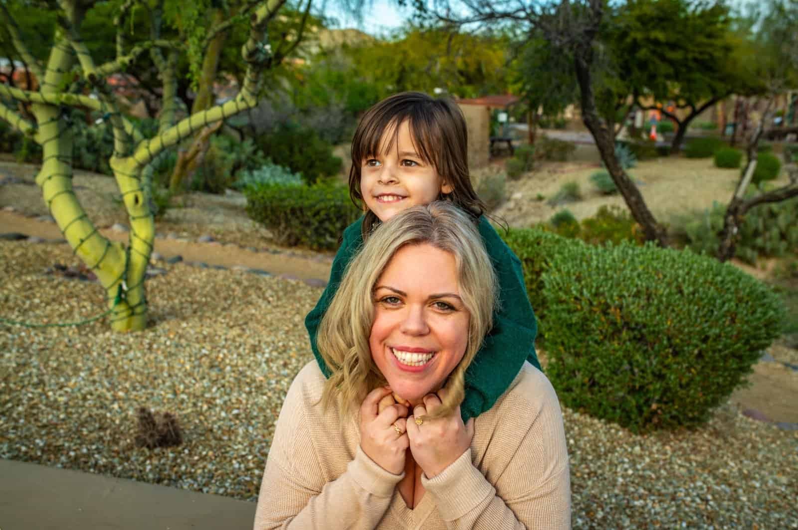 Joyful mother and daughter sharing a special moment outdoors in a lush, green park setting.