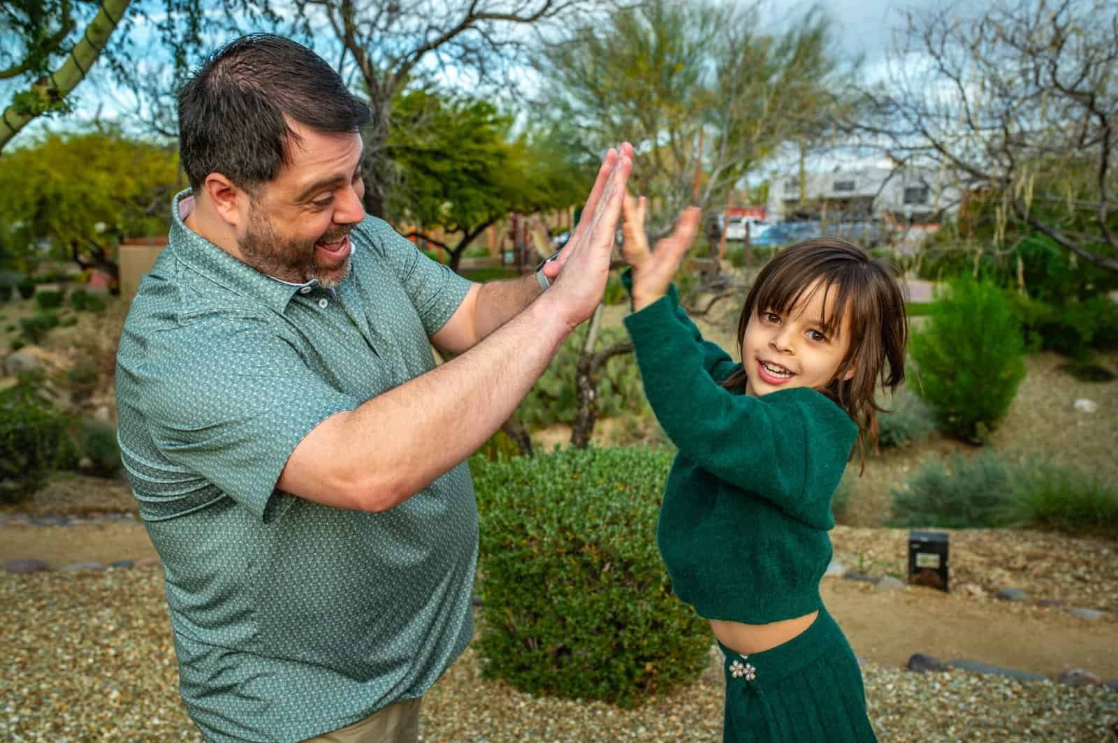 A father and daughter celebrating together outdoors, capturing a joyful moment of bonding and happiness.