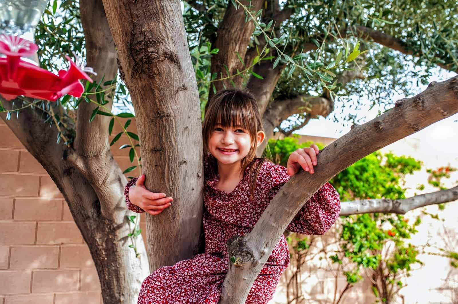 Joyful girl enjoying nature and family moments in a backyard setting with lush greenery and sunlight.
