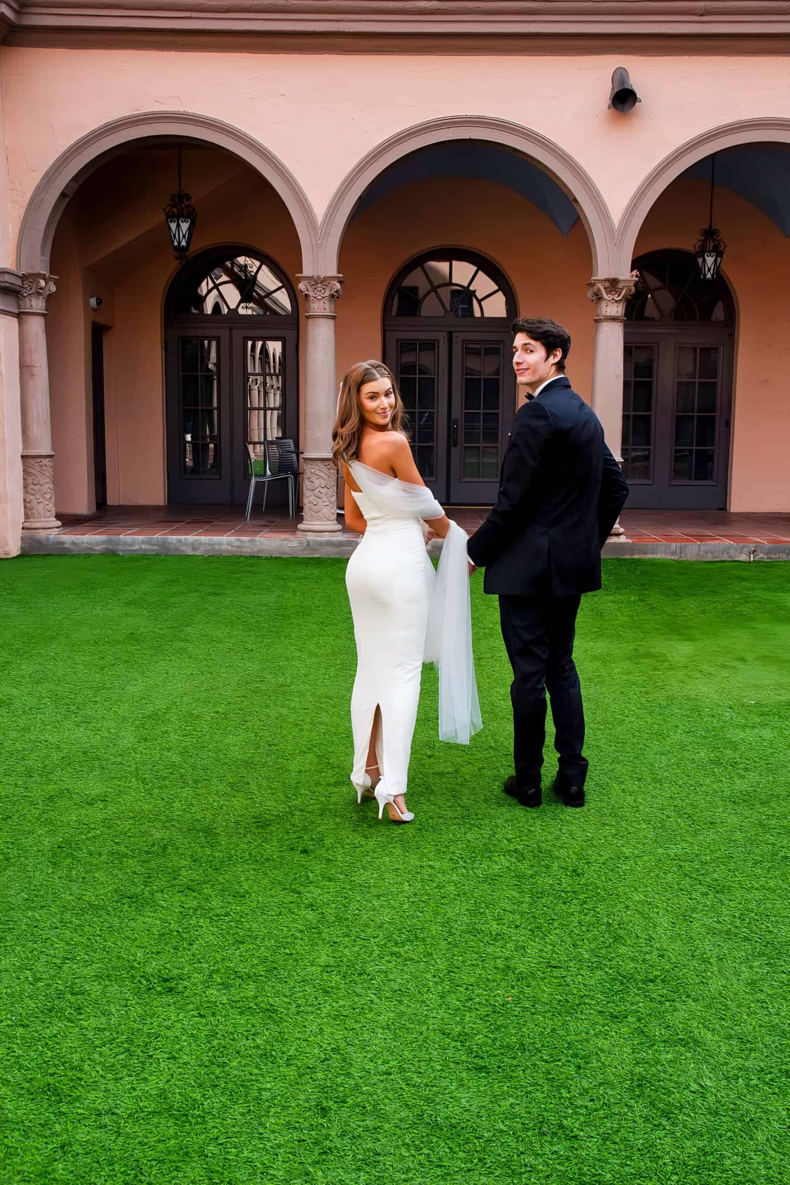 Beautiful wedding photo capturing joyful couple at a historic venue with lush grass.