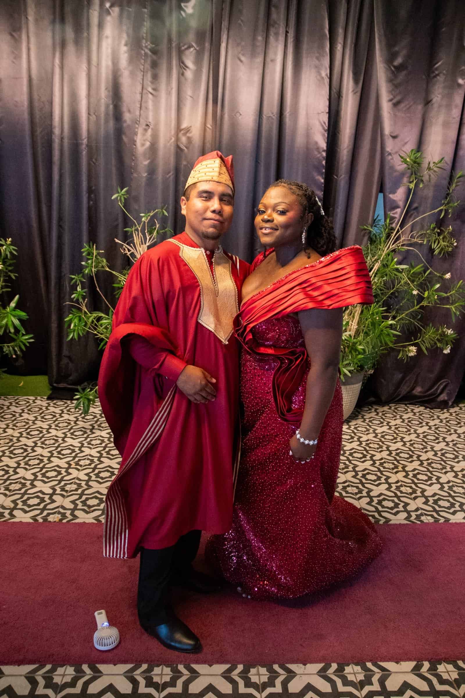 A couple dressed in vibrant traditional clothing at a cultural celebration, smiling and posing for the camera.