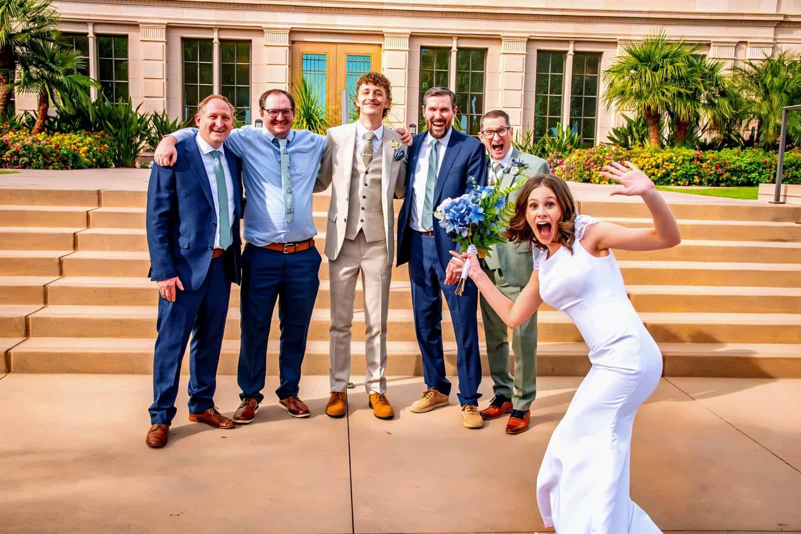 Joyful wedding group photo with bride and friends on steps.