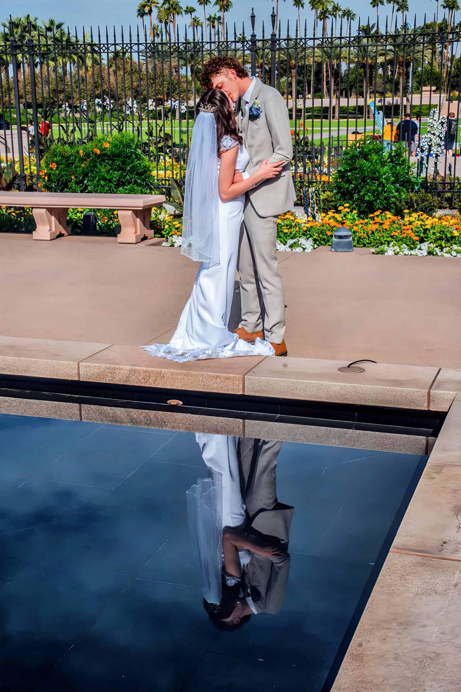 A beautiful wedding scene featuring a couple sharing an intimate moment beside a reflective pool in a lush garden setting.