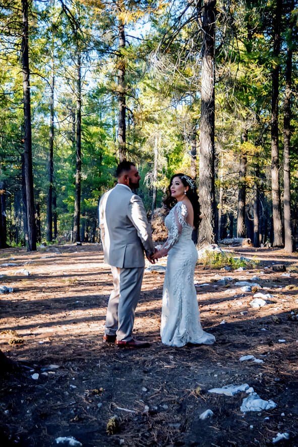 Beautiful wedding moment captured in a lush forest setting with sunlight filtering through trees.