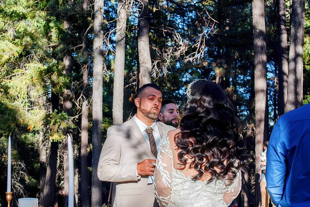 A beautiful outdoor wedding in the woods featuring a bride and groom during their vows, surrounded by nature.
