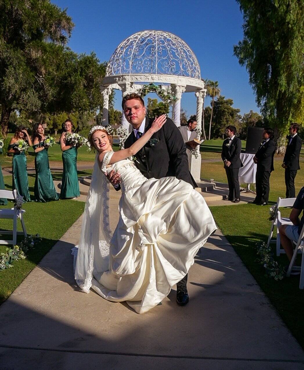 A joyful moment of the bride and groom dancing at their outdoor wedding ceremony.