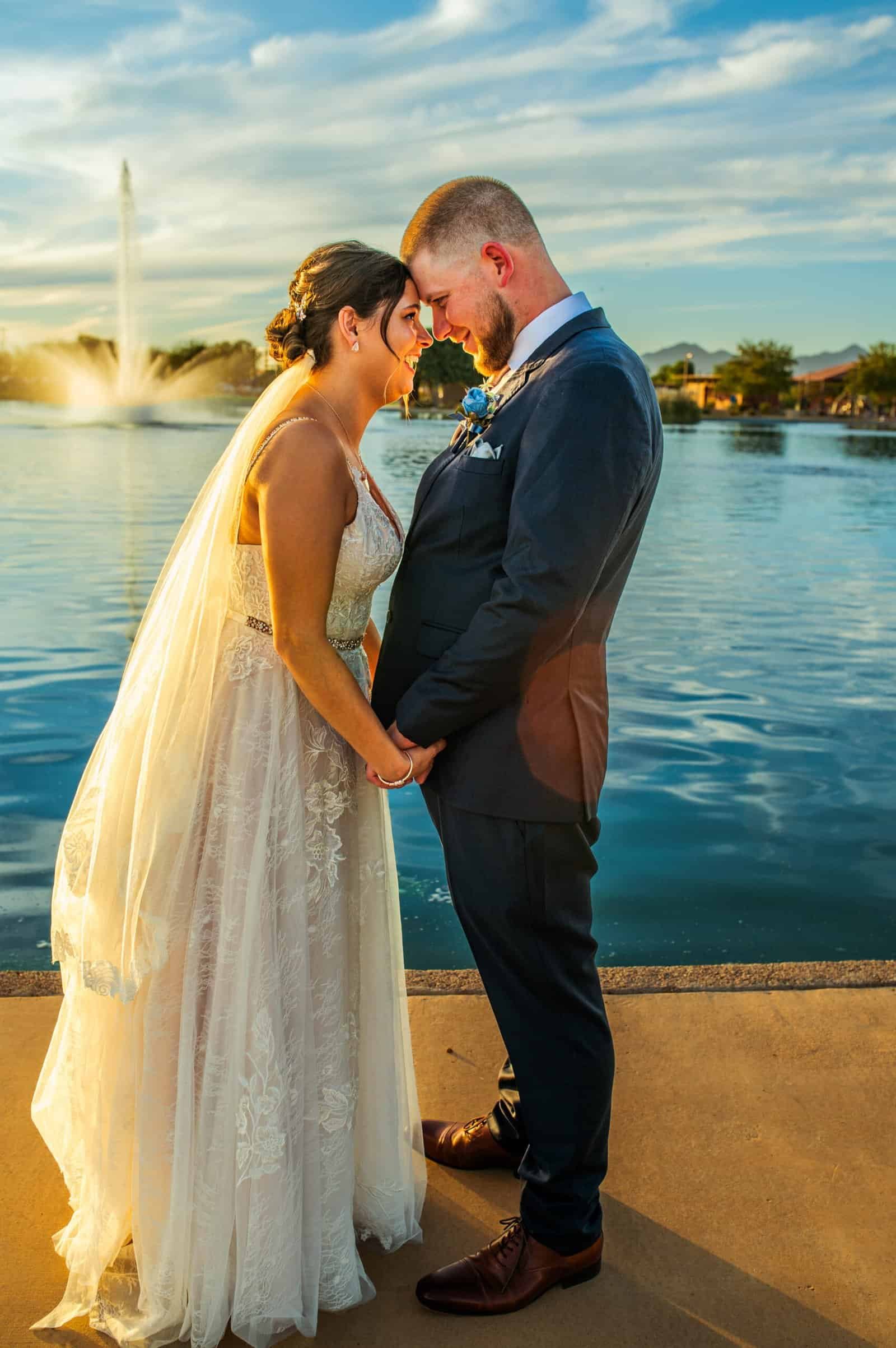 Beautiful wedding scene with a couple embracing by a fountain at sunset, capturing love and happiness.