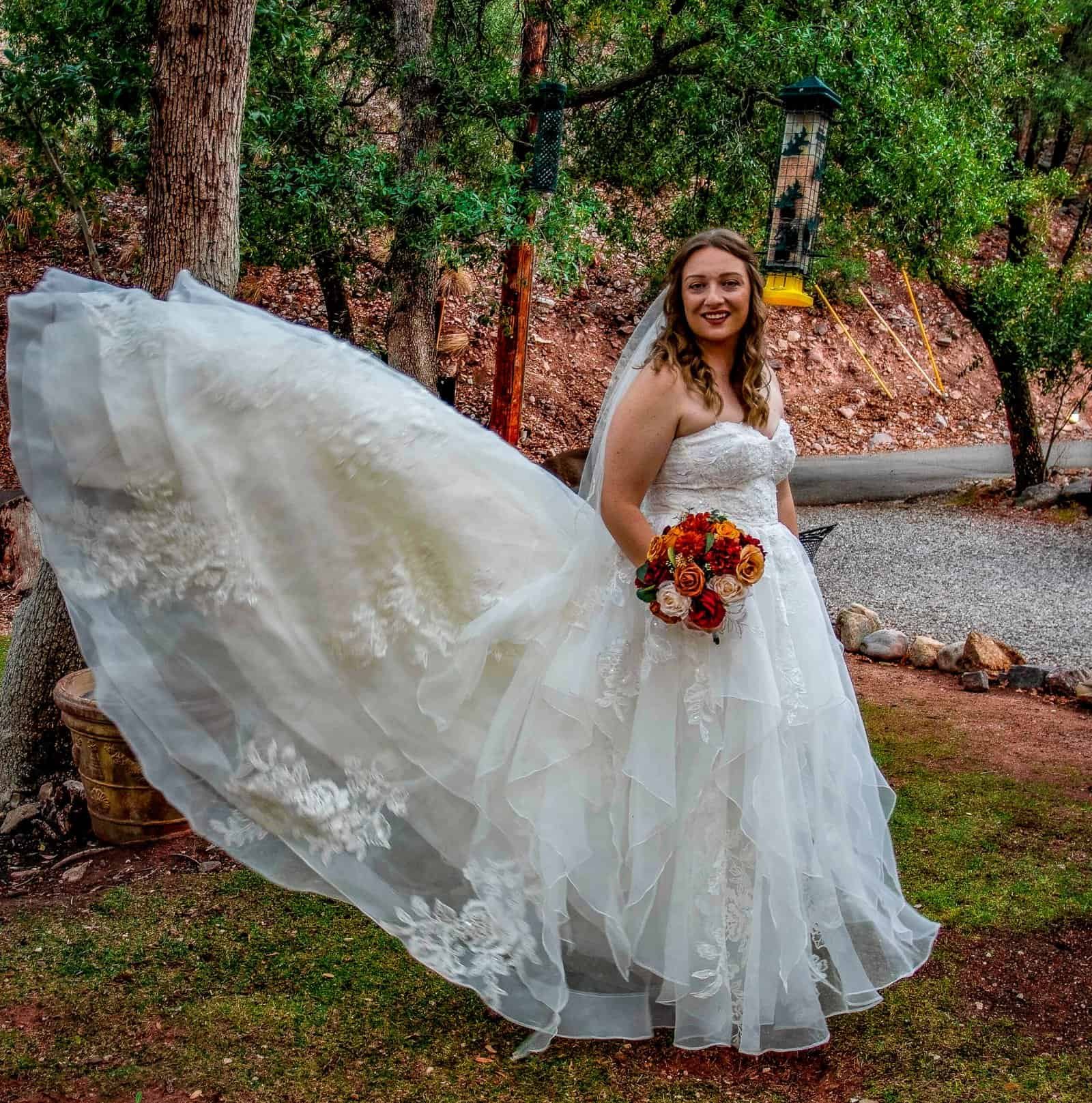 Beautiful outdoor wedding scene with bride in elegant gown and vibrant bouquet.