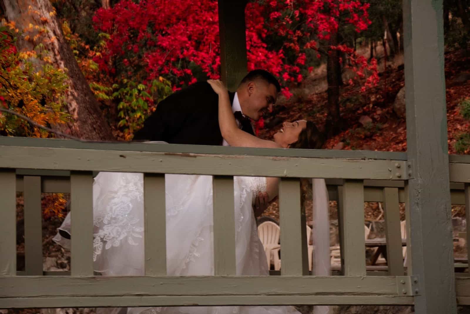 Beautiful wedding moment captured outdoors with vibrant fall foliage in the background.