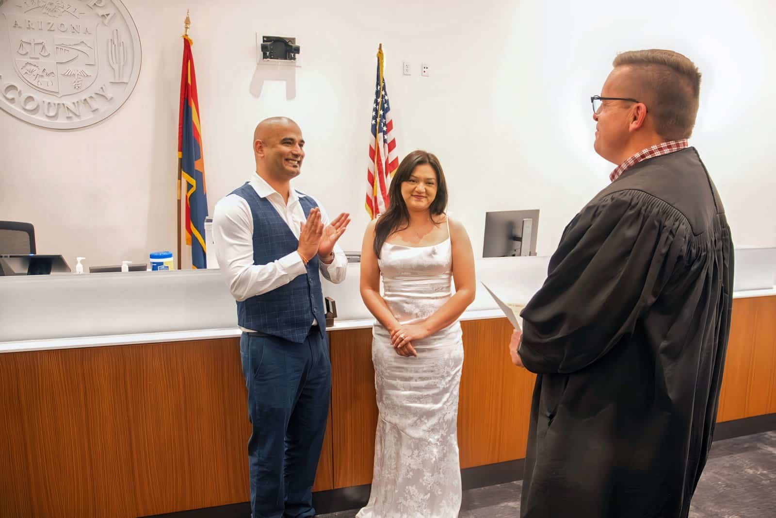 Joyful wedding moment with couple and officiant in a formal setting.