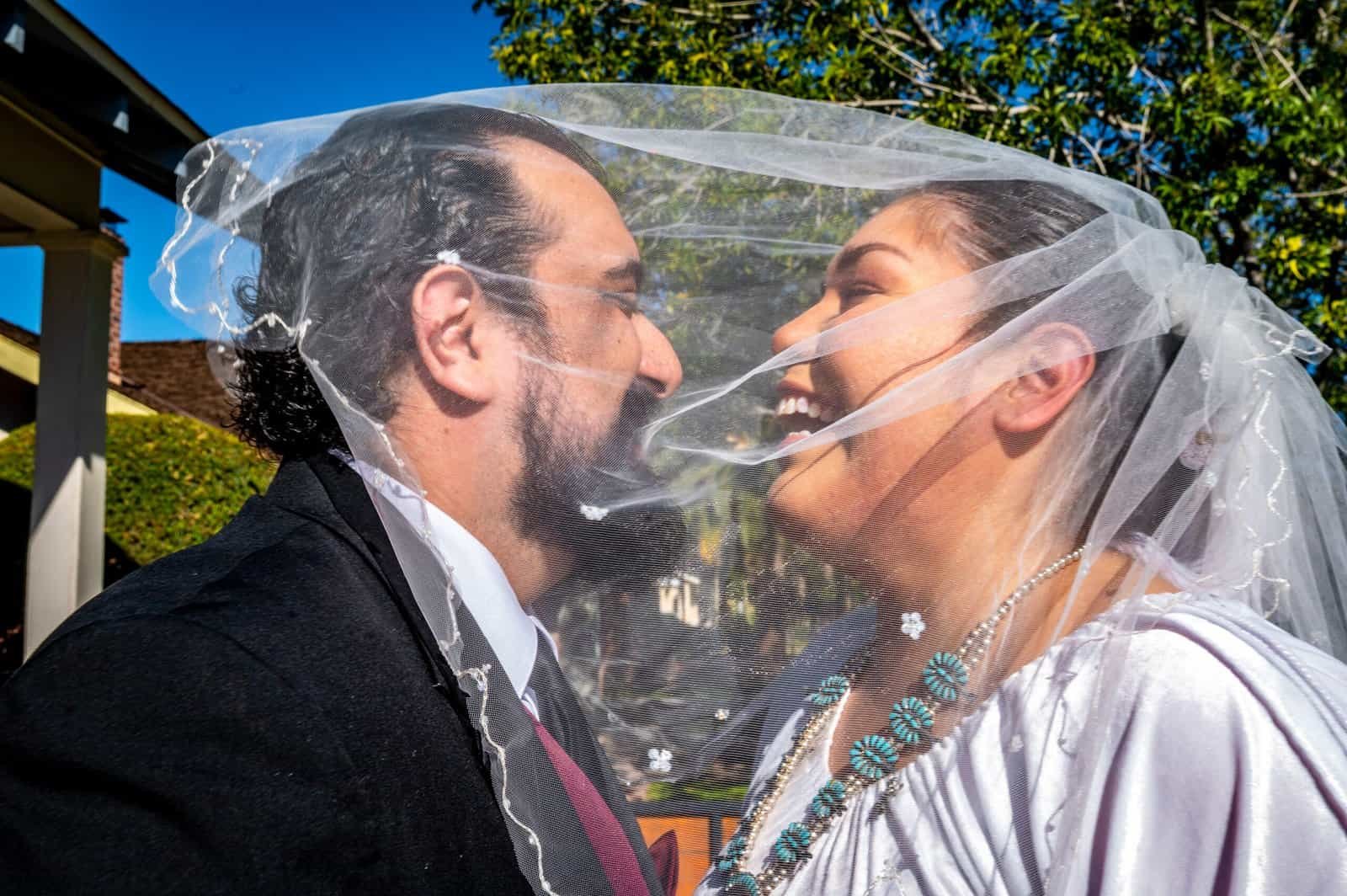 A happy bride and groom share a playful moment during their wedding photoshoot outside.