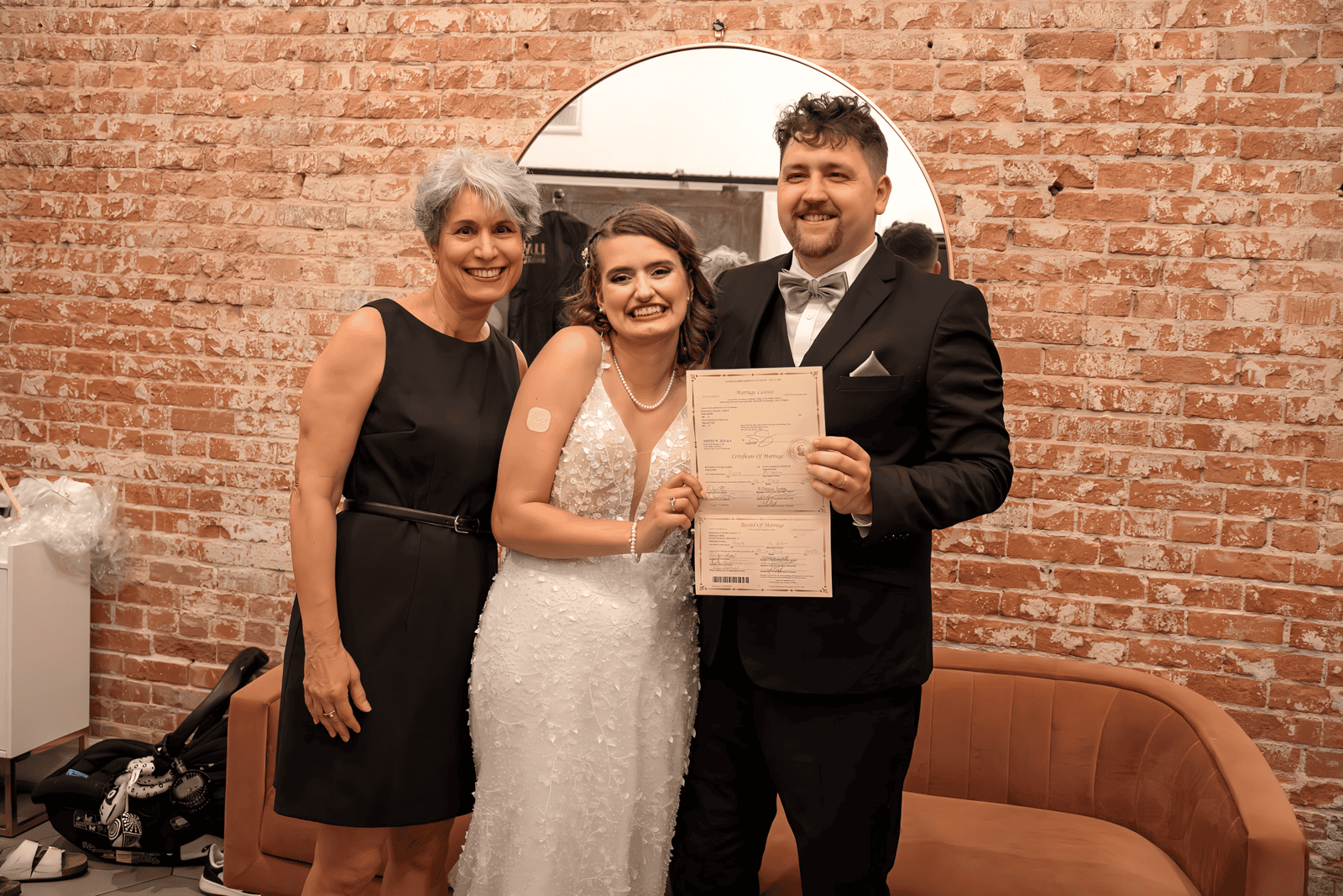 A joyful wedding moment featuring a bride, groom, and family member in a cozy indoor setting.