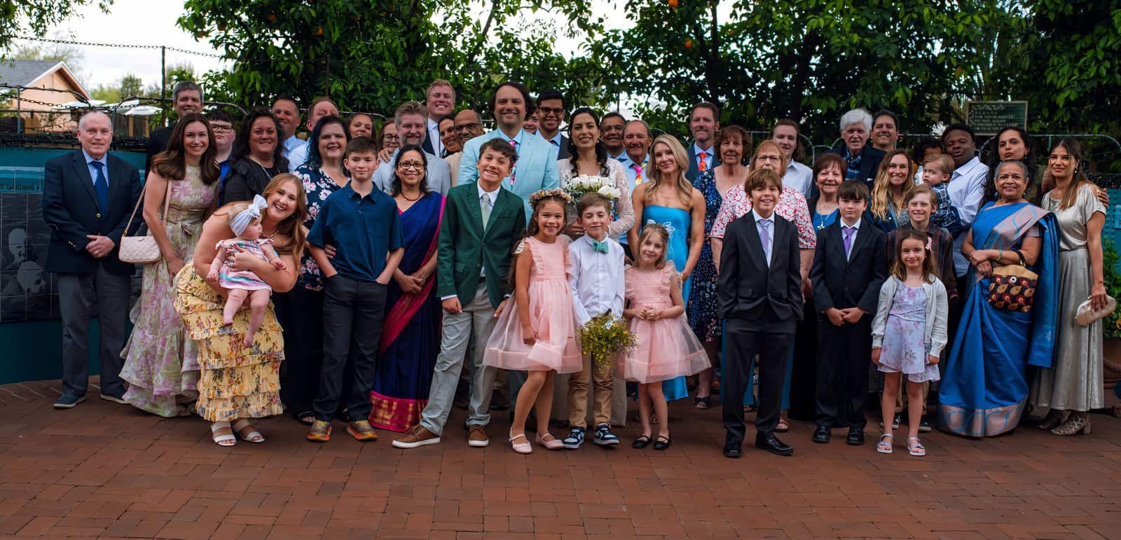 A large family gathered together for a group photo during a wedding celebration outside.