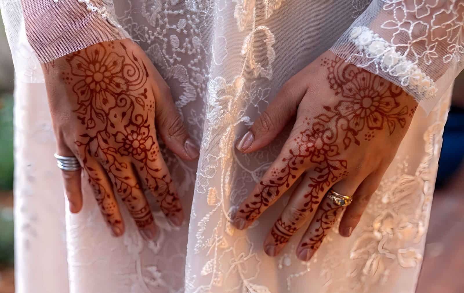Close-up of intricately decorated hands with henna, showcasing traditional wedding body art and jewelry details.