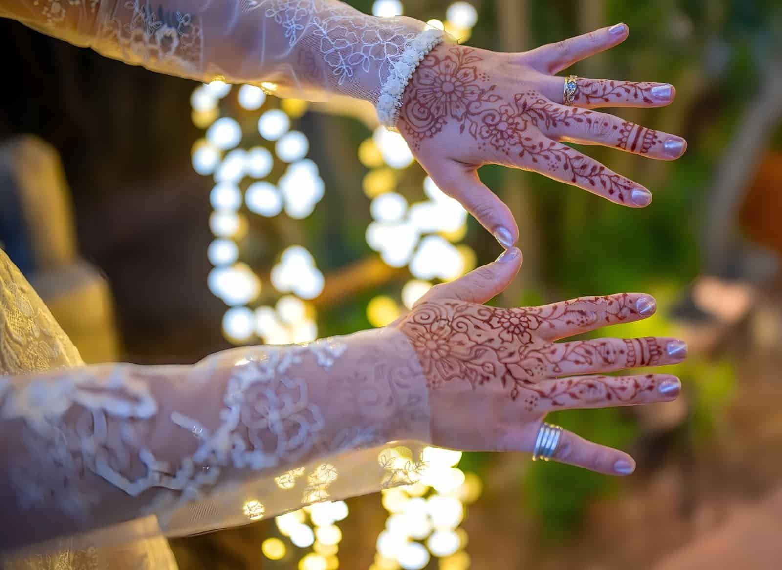Close-up of hands decorated with detailed henna art for a wedding celebration.