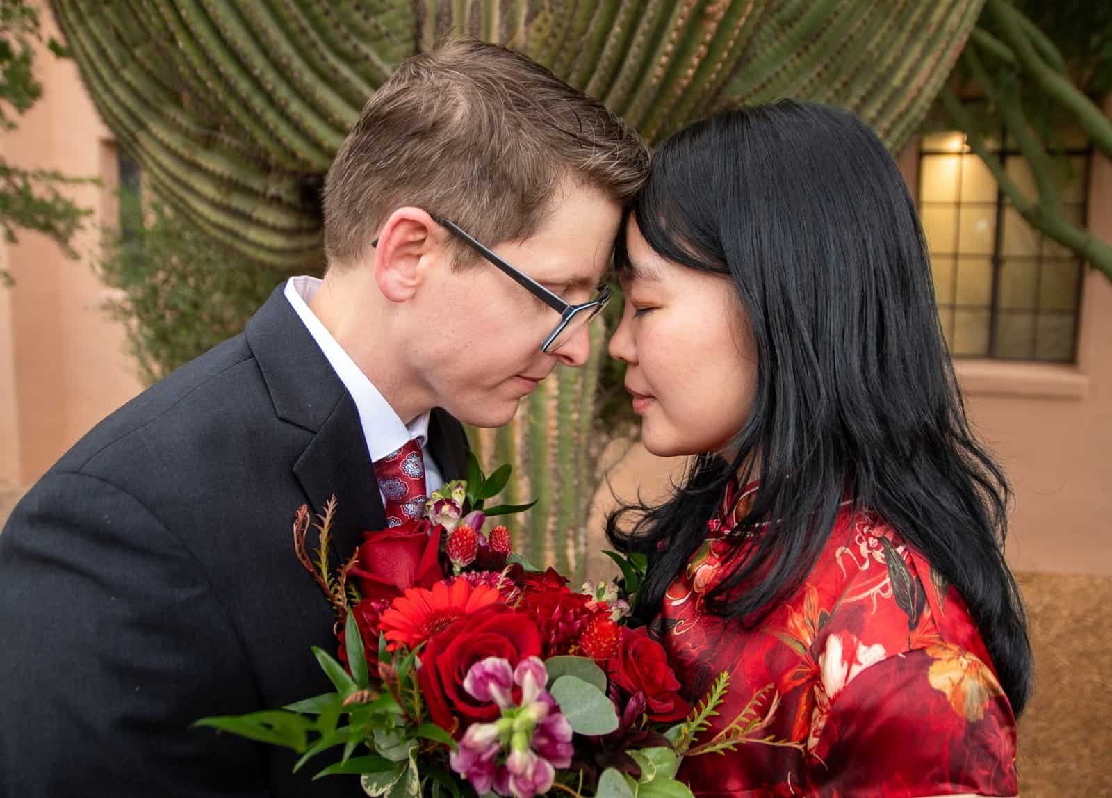 A couple sharing an intimate moment, holding a bouquet of vibrant flowers, perfect for wedding or engagement photography.