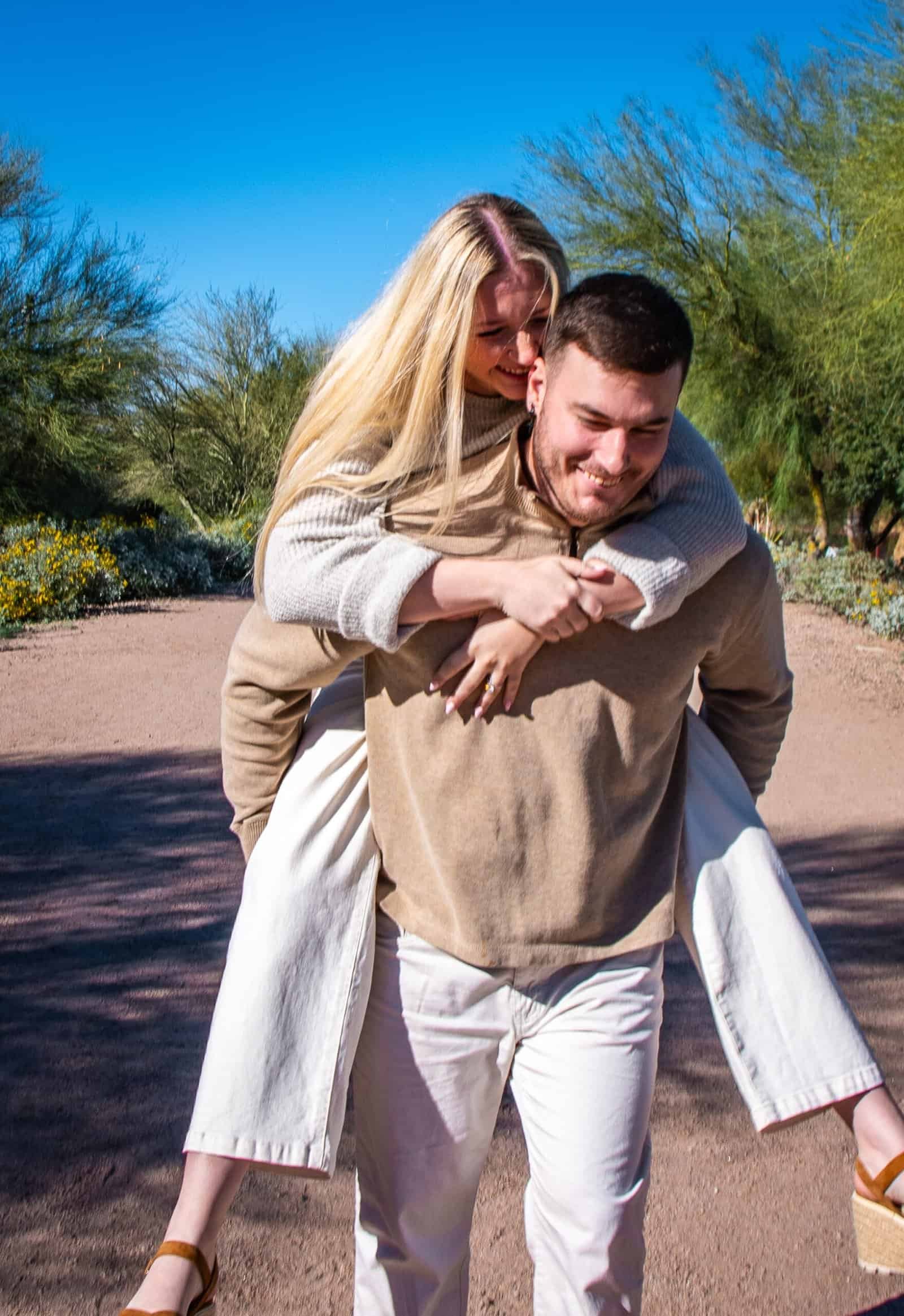 Joyful couple sharing a playful moment during a walk in a scenic park setting.