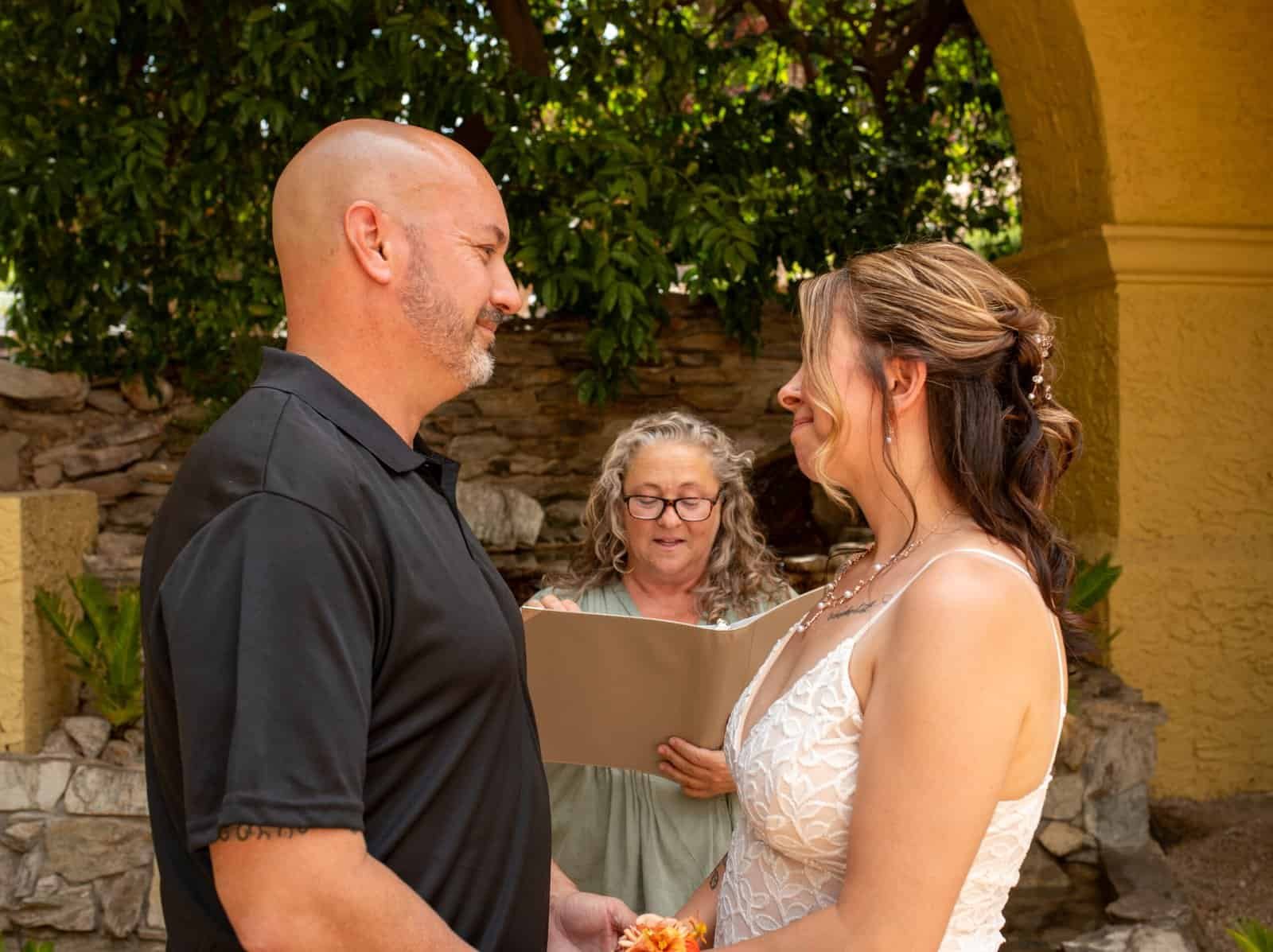 Beautiful outdoor wedding ceremony with couple exchanging vows and officiant present.