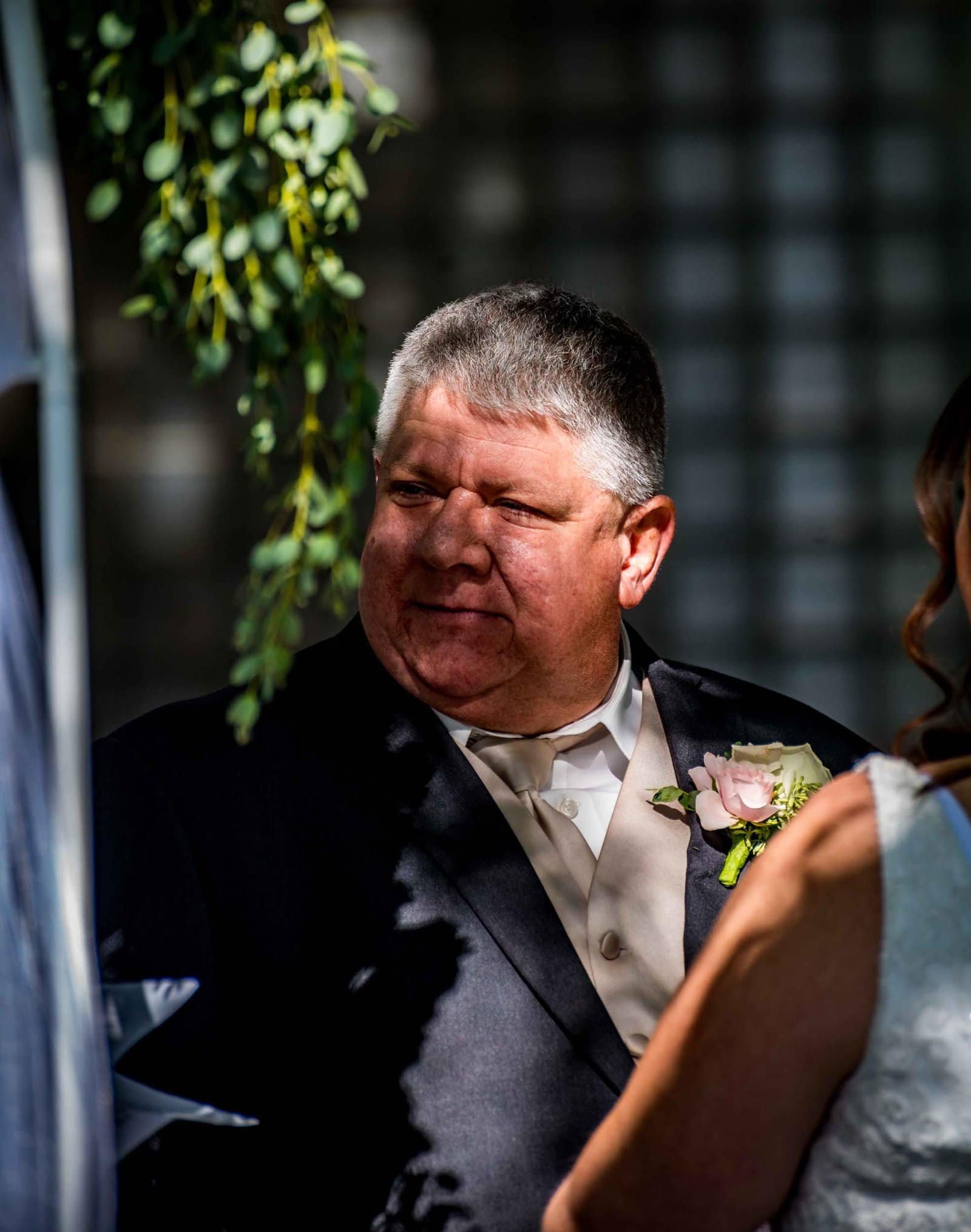 A wedding officiant standing during a ceremony, with a groom in focus, capturing a special moment.