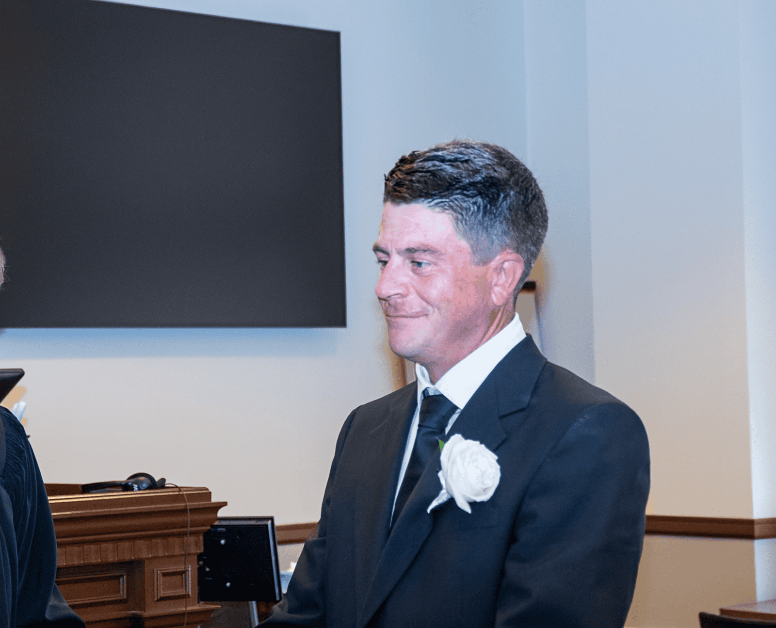 Wedding groom in formal attire with boutonniere at special moment video shoot.