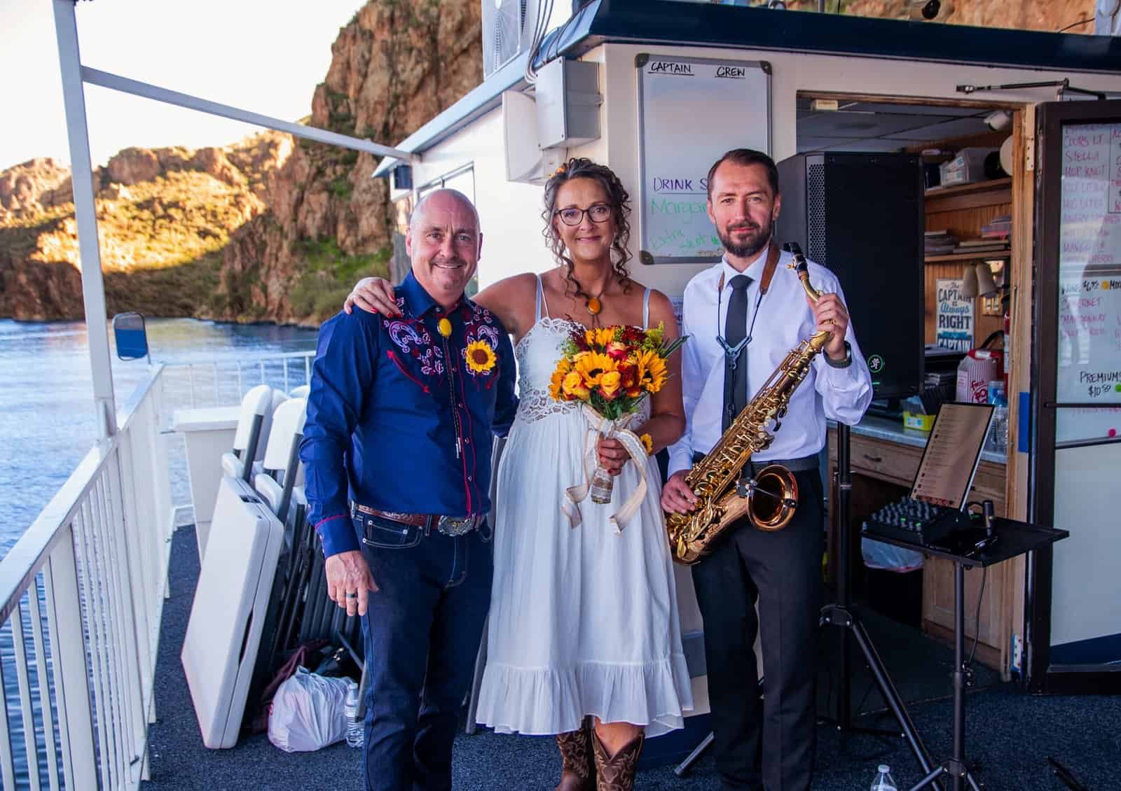 Joyful wedding moment featuring bride and musicians on a scenic boat deck.