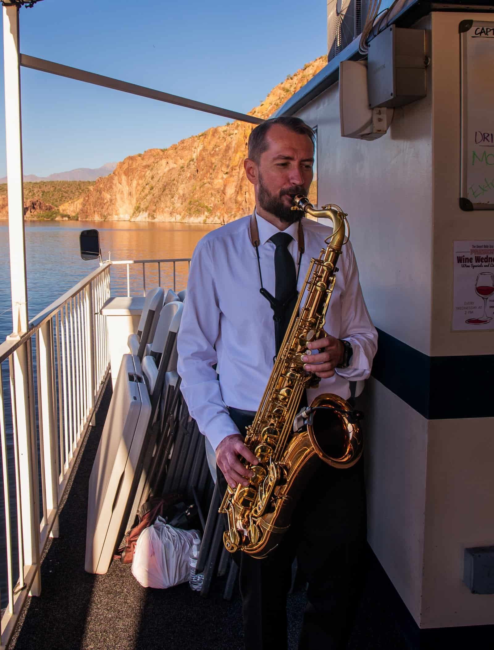 A professional saxophonist dressed in formal attire performs live music on a boat, creating a memorable experience for guests with beautiful water and.