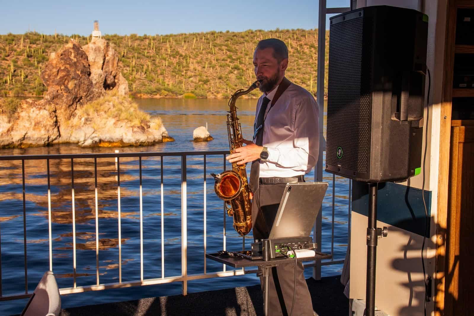 Live outdoor music performance on a boat with scenic water and rocky island backdrop.