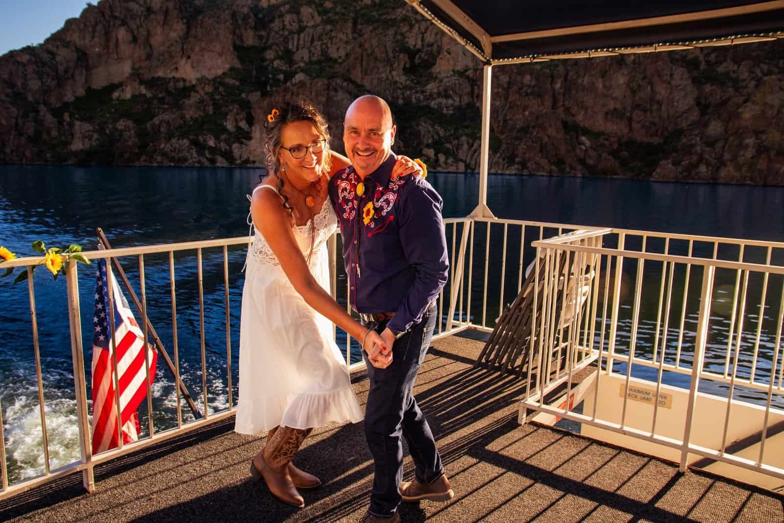 Joyful couple dancing together on a boat deck during sunset, capturing a special moment of love and celebration.