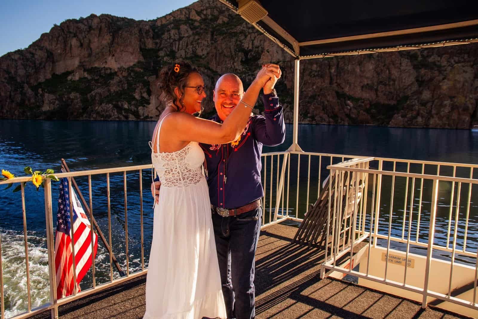 Romantic moment captured of a couple dancing and enjoying their special day on a boat with stunning natural scenery.