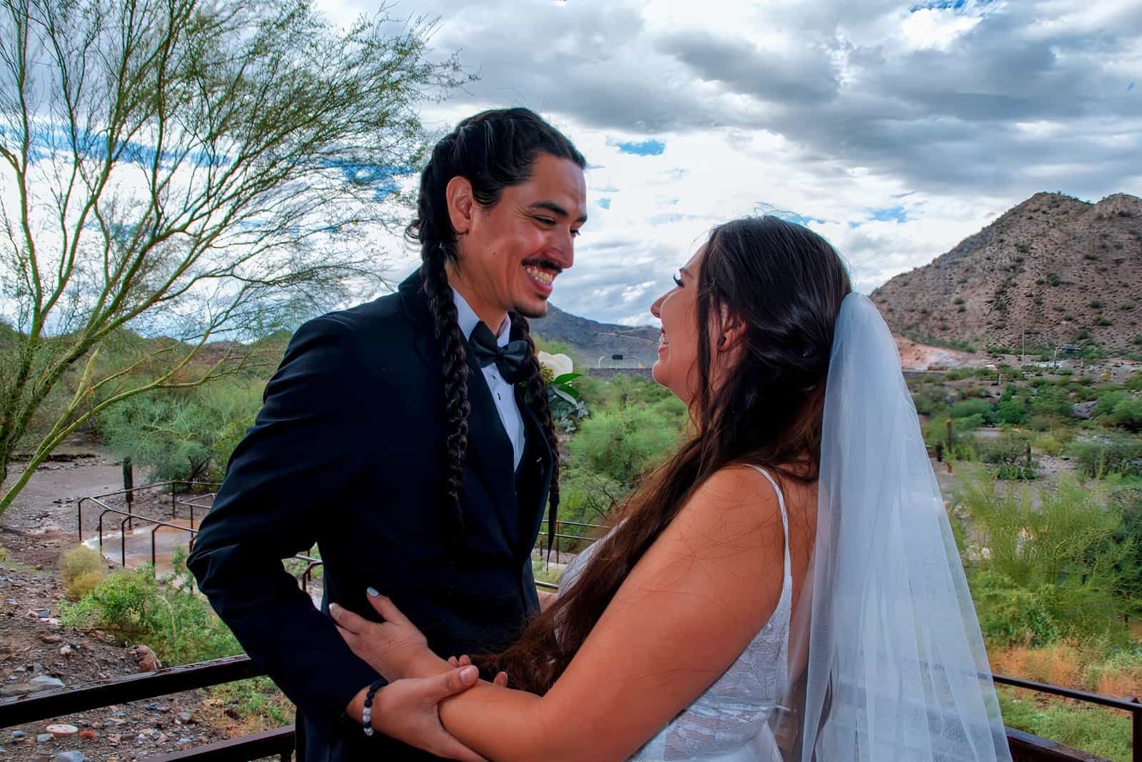 A joyful bride and groom sharing a special moment outdoors, surrounded by desert scenery and mountains.