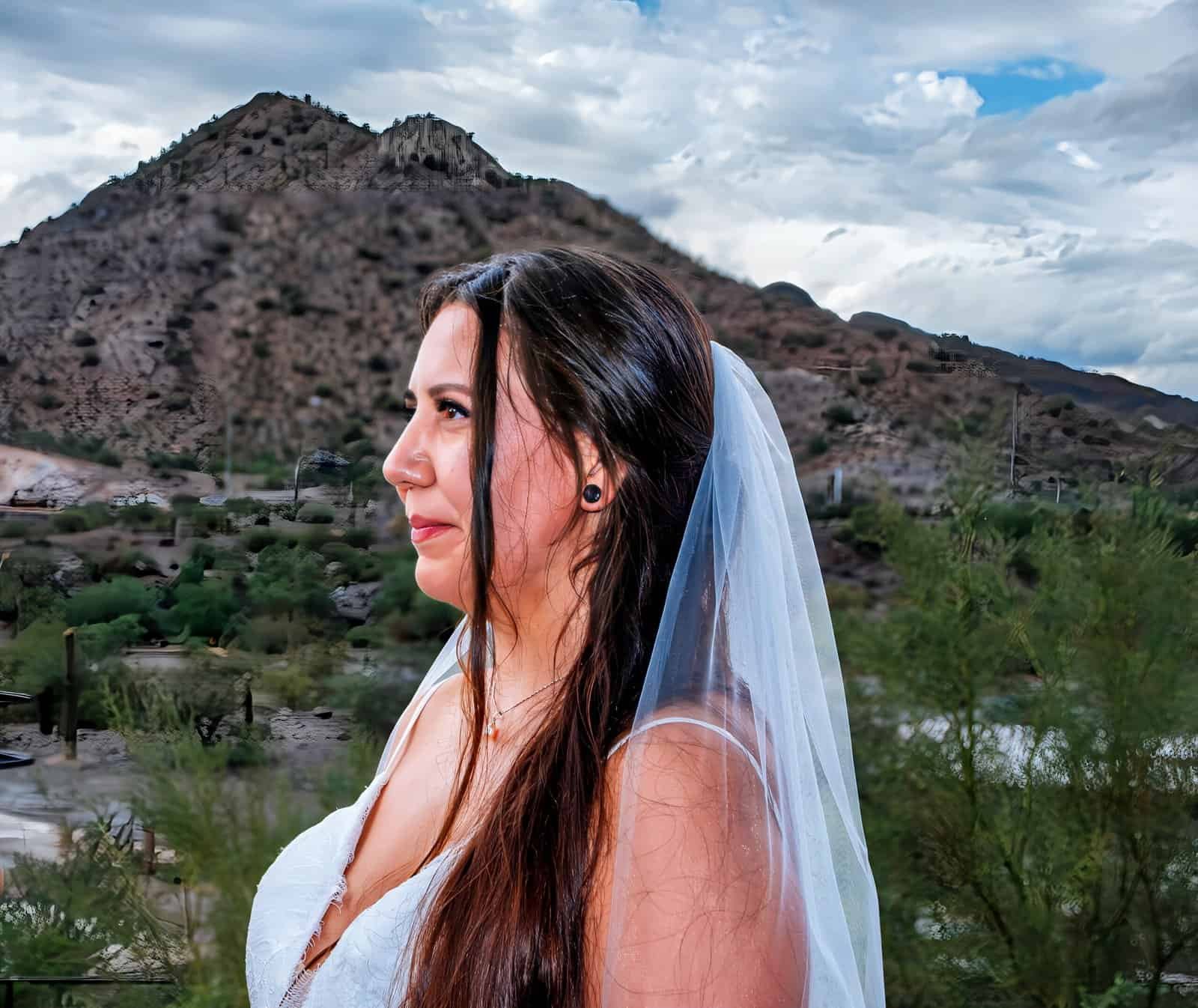 Beautiful bride in wedding dress with mountain landscape and cloudy sky, ideal for special moments.
