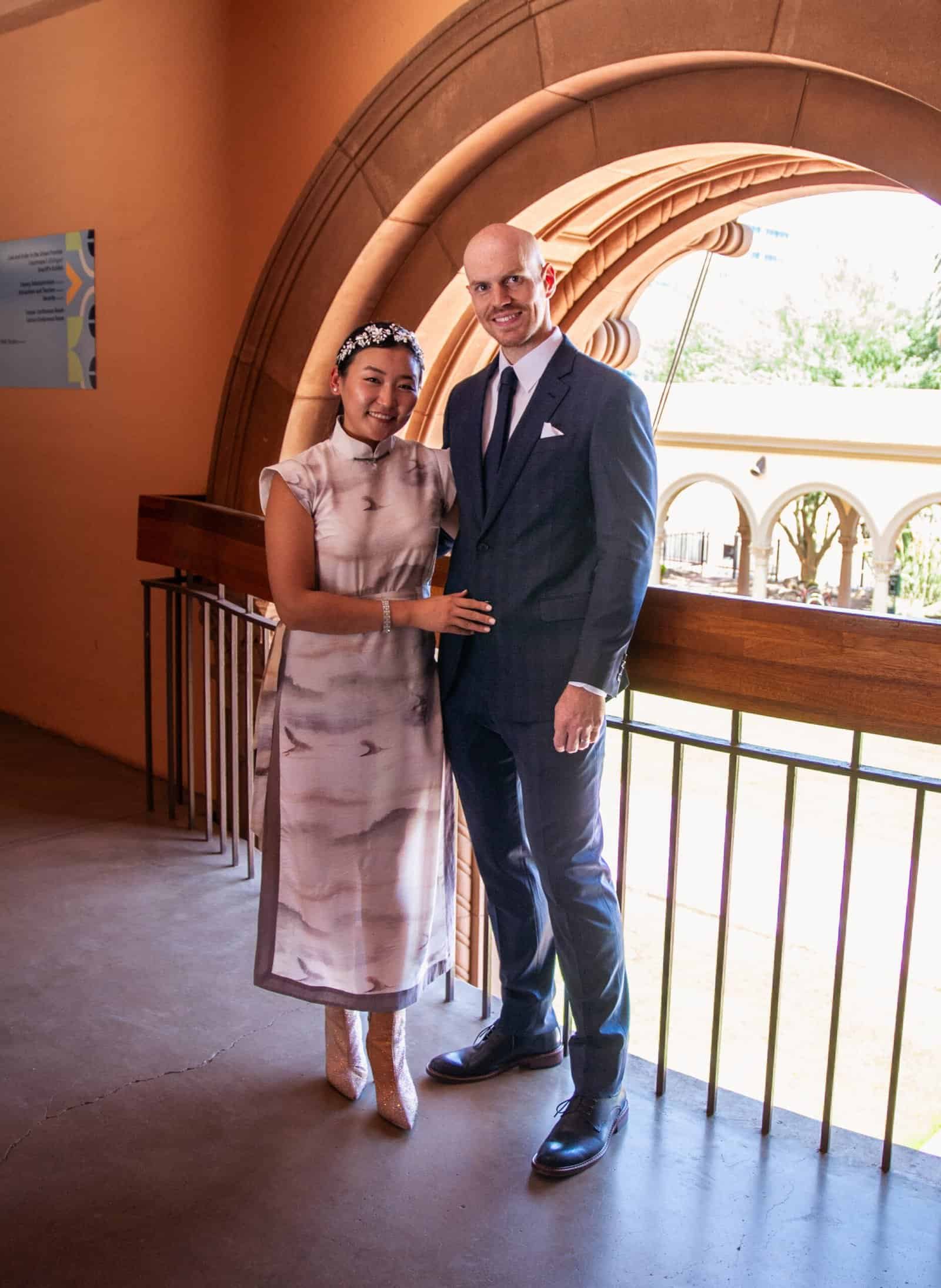 A joyful bride and groom pose together at a wedding venue with stunning architecture and bright natural lighting, capturing a special moment.