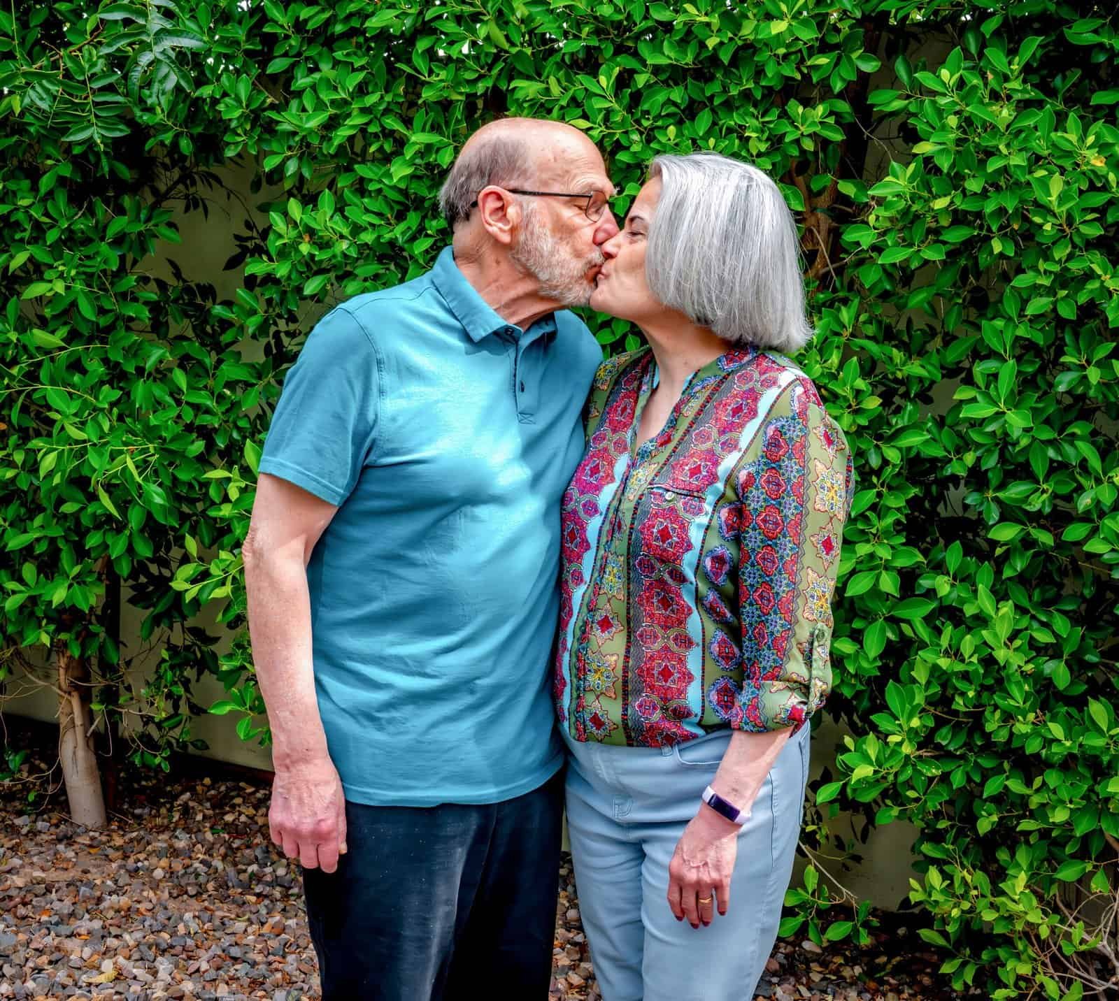 A loving elderly couple kisses in a garden, symbolizing enduring love and companionship, perfect for wedding or anniversary video highlights.
