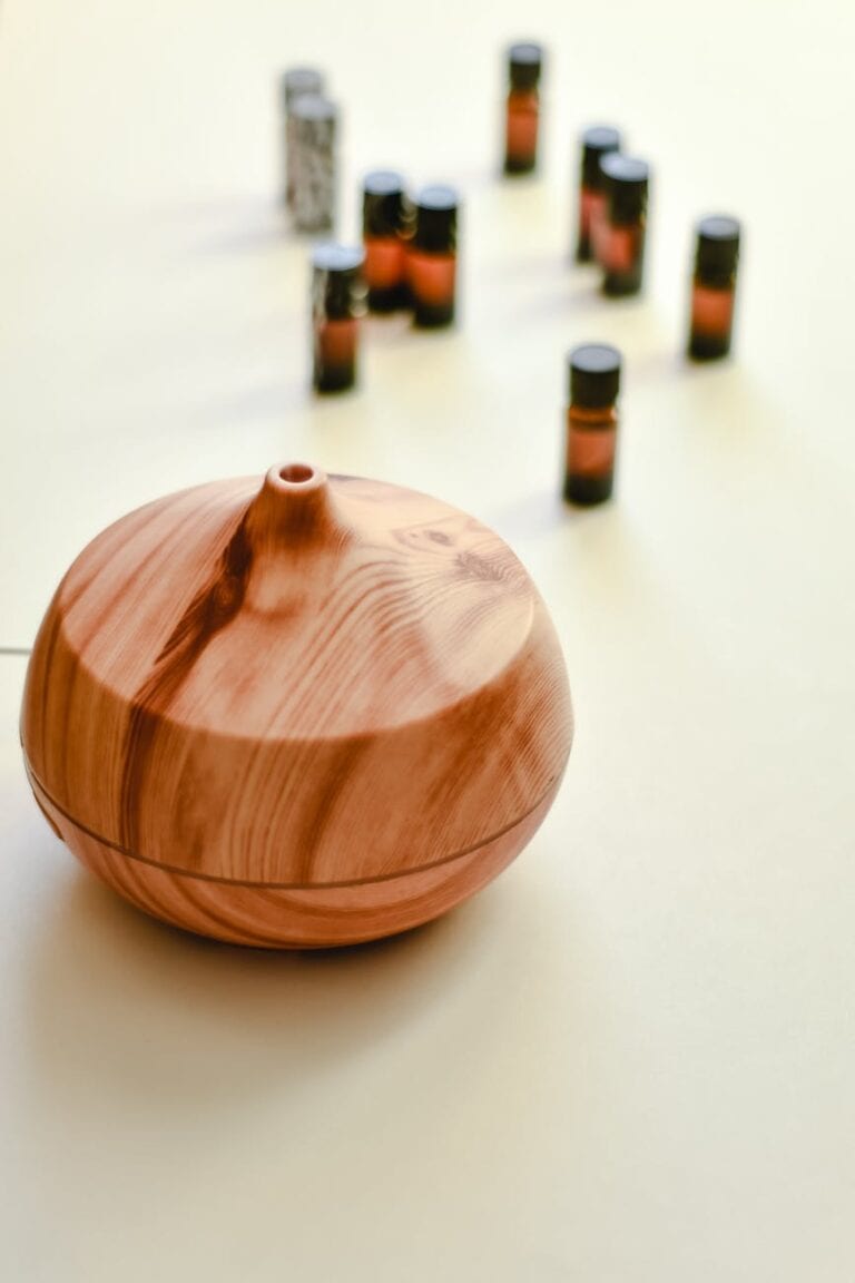 wooden oil diffuser on white surface with essential oils in the background