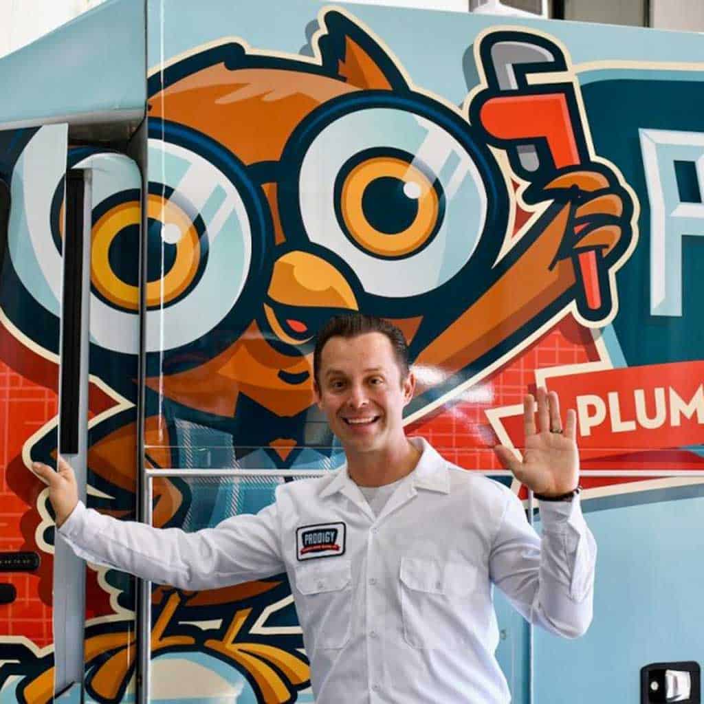 A friendly plumber from Prodigy Sewer and Drain stands next to a service van, ready to help with plumbing needs.