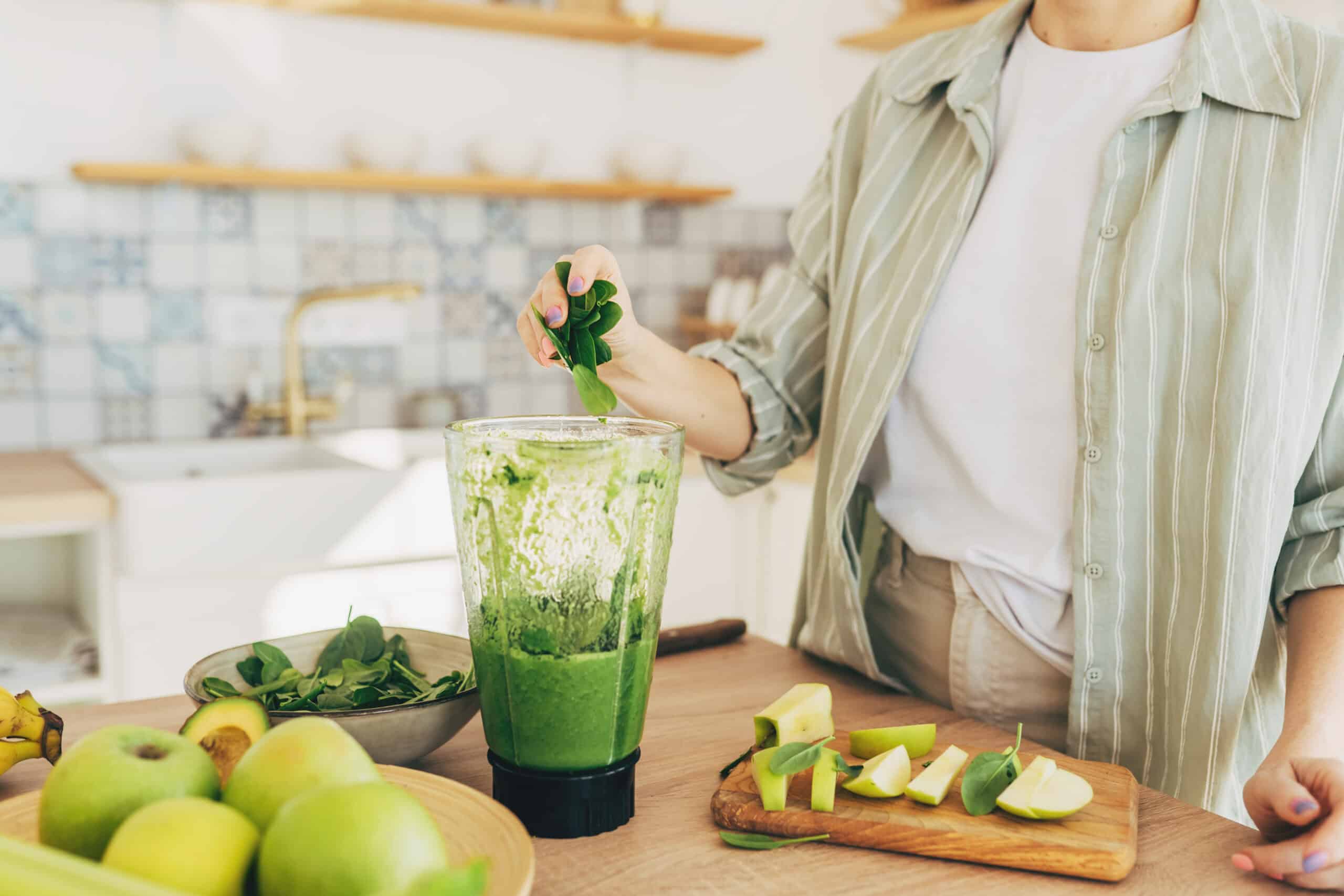 Young man preparing healthy green smoothie in kitchen