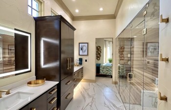 A double floating vanity with rich wood cabinetry and integrated under-cabinet lighting provides both storage and visual impact from Stanton and Company.