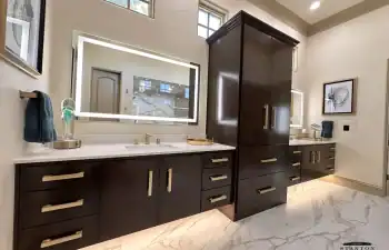 A double floating vanity with rich wood cabinetry and integrated under-cabinet lighting provides both storage and visual impact from Stanton and Company.
