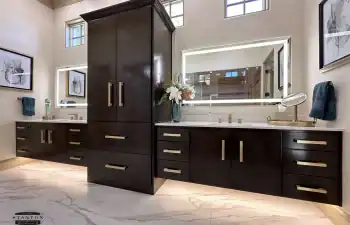 A double floating vanity with rich wood cabinetry and integrated under-cabinet lighting provides both storage and visual impact from Stanton and Company.