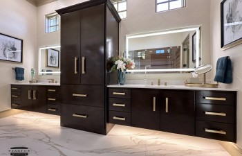 A double floating vanity with rich wood cabinetry and integrated under-cabinet lighting provides both storage and visual impact from Stanton and Company.