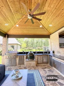 Outdoor kitchen with natural stone countertops and a built-in grill in a Fort Worth backyard