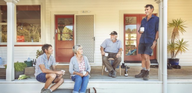 Family on front deck of house drinking tea
