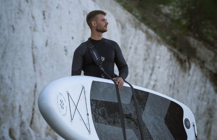 What Do You Wear Under a Wetsuit? 1 What do you wear under a wetsuit? Man in a wetsuit carrying a SUP