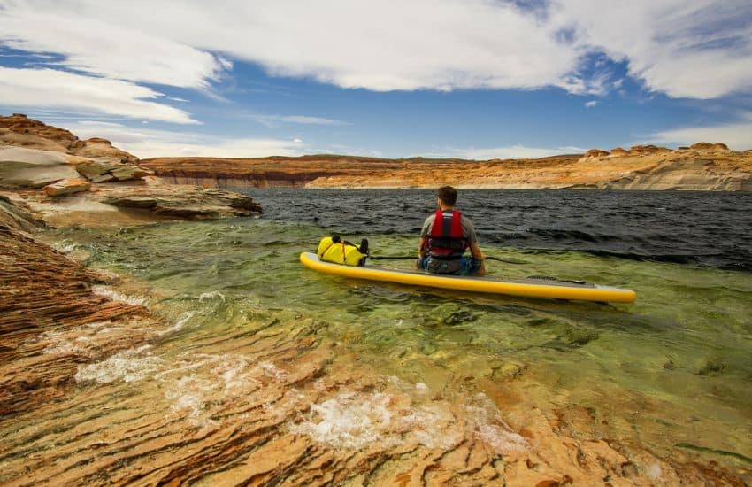 19 Things I Wish I Knew When I Started Stand Up Paddle Board 22 Paddle boarder wearing life jacket sat on his board