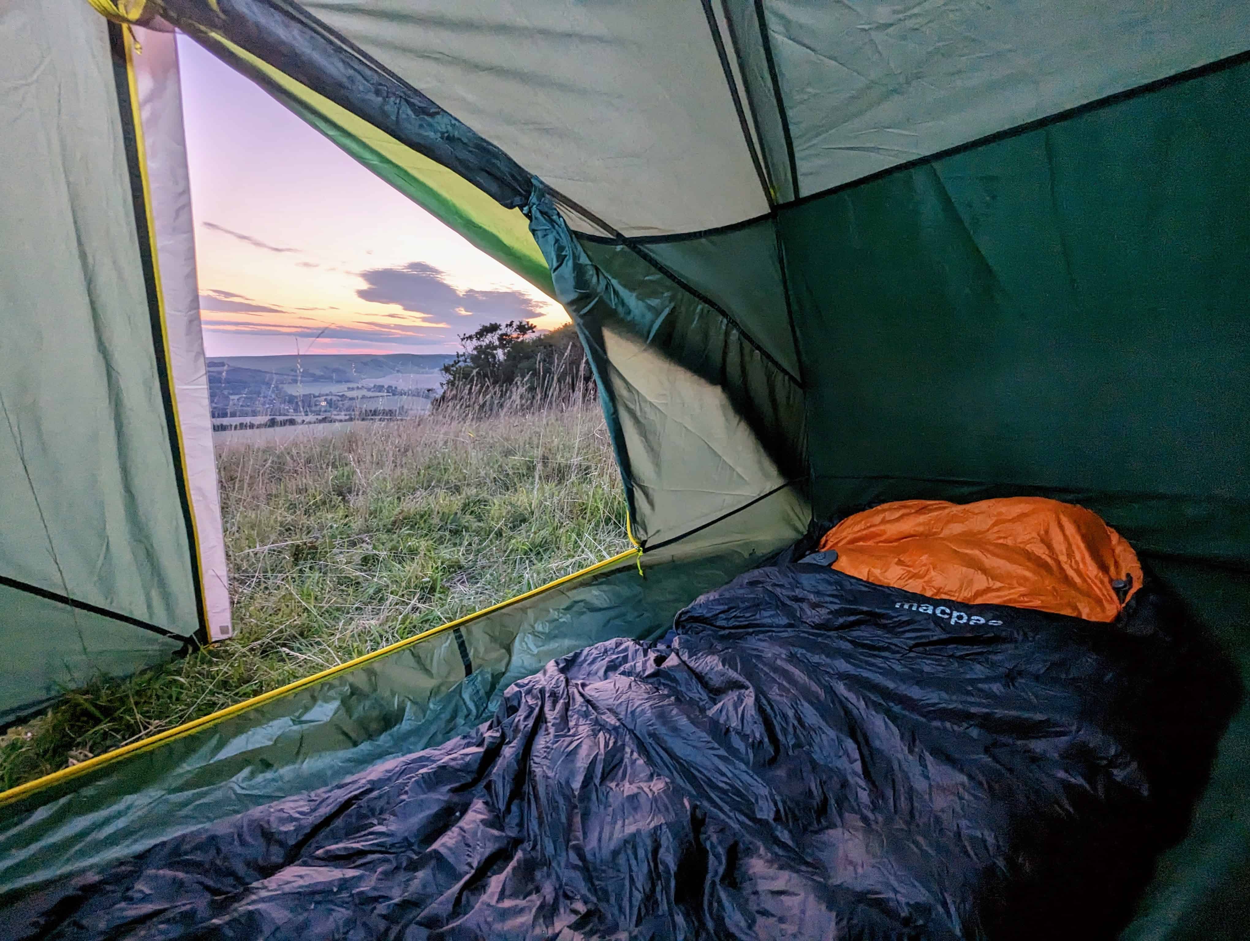 Wild Camping Equipment: Essential Kit List for 2025 4 Sleeping bag laid out inside a tent with a view of the sunset