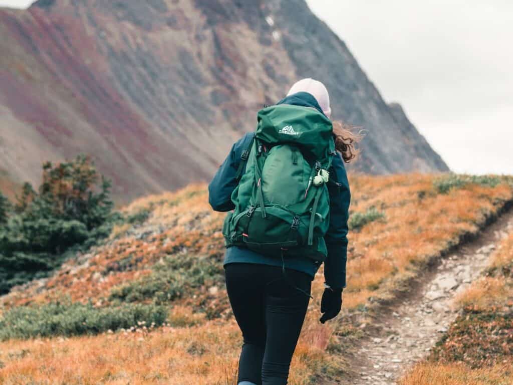 Wild Camping Equipment: Essential Kit List for 2025 12 Woman Hiking up a mountain wearing a green backpack