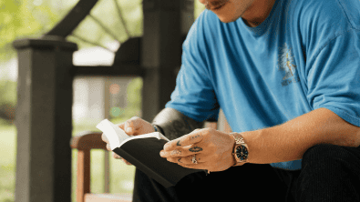 Man reading a book outdoors at Still Waters retreat.