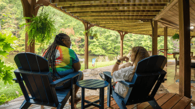Outdoor seating with two women relaxing on a porch.