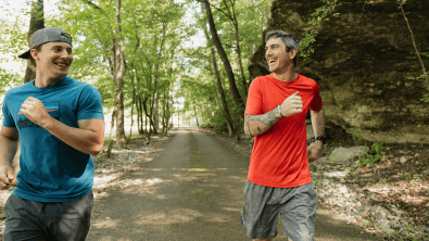 Two men jogging on a peaceful forest trail near Still Waters.